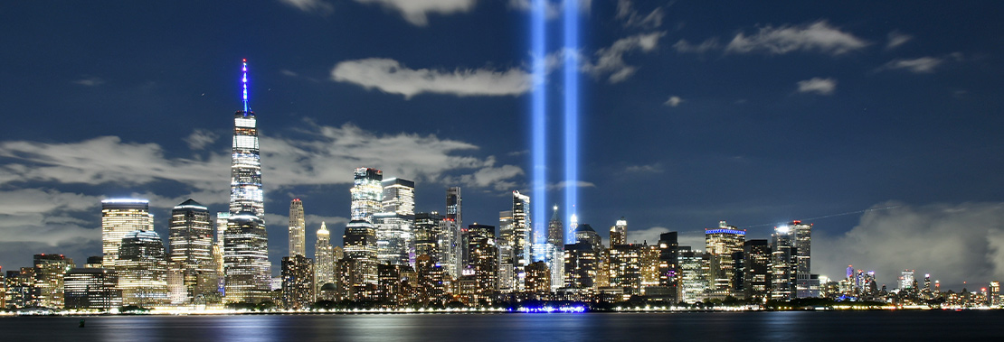 A skyline view of New York with the World Trade Center Lights lit up in the night sky