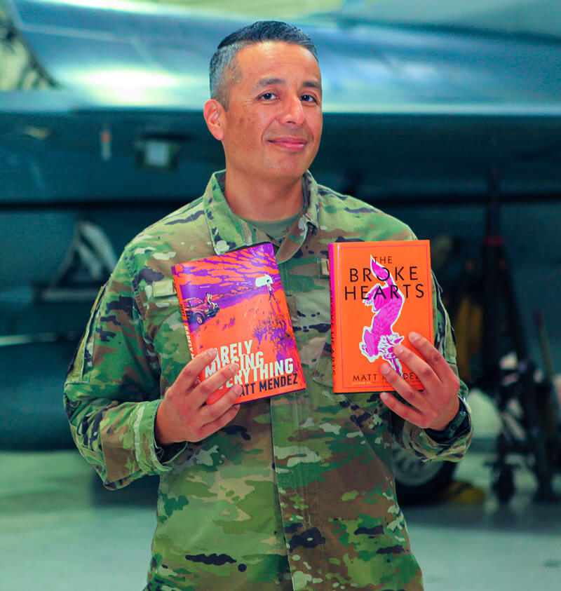 Matt Mendez holds up his two books