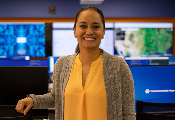 Tauty Sanchez wearing a yellow shirt facing the camera standing inside the IT Center of Excellence at Pima. 