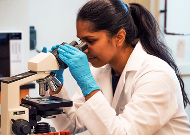 A medical tech looks into a microscope