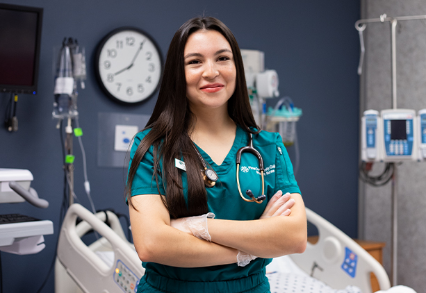 Lizbeth Mora stand facing the camera with arms crossed and smiling.