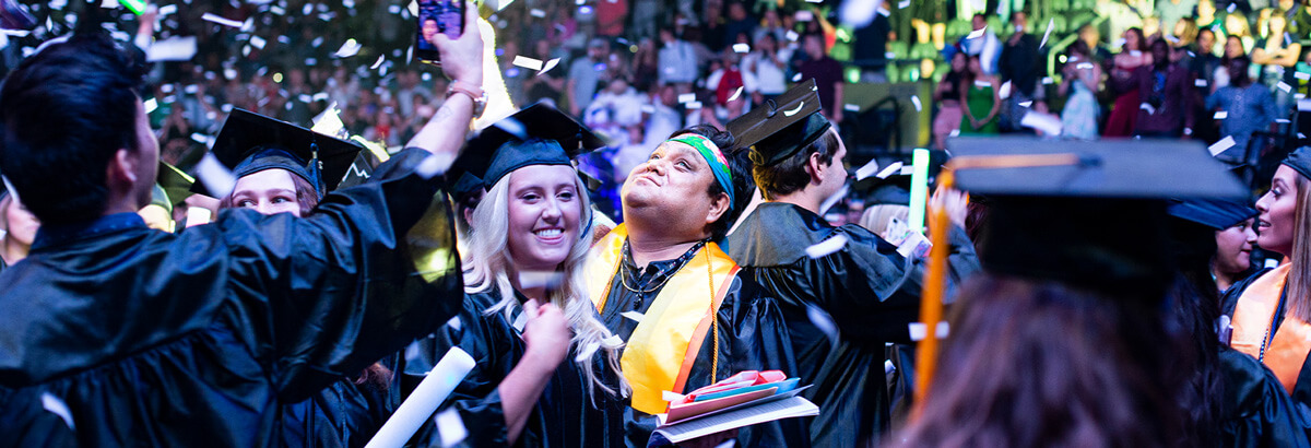 Two Pima Graduates Celebrate at Graduation while confetti flalls