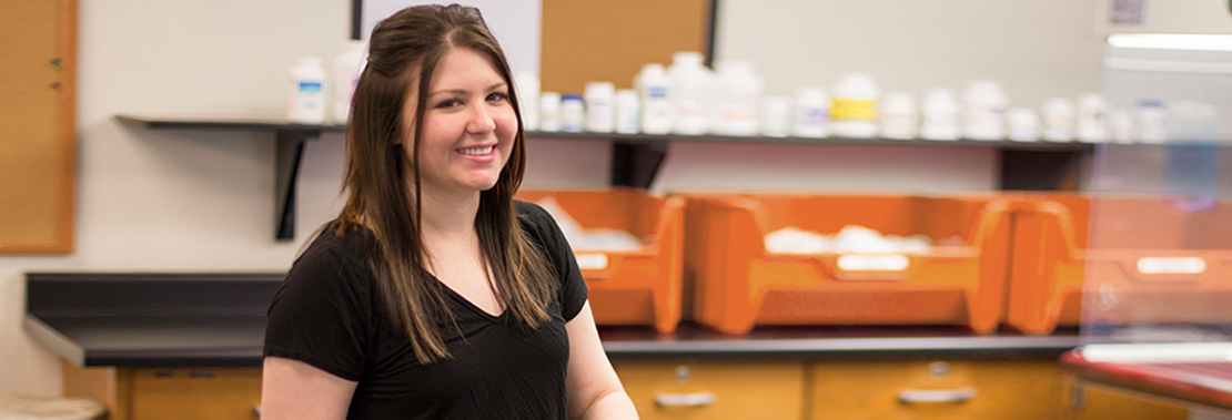 A student sits in a science classroom smiling