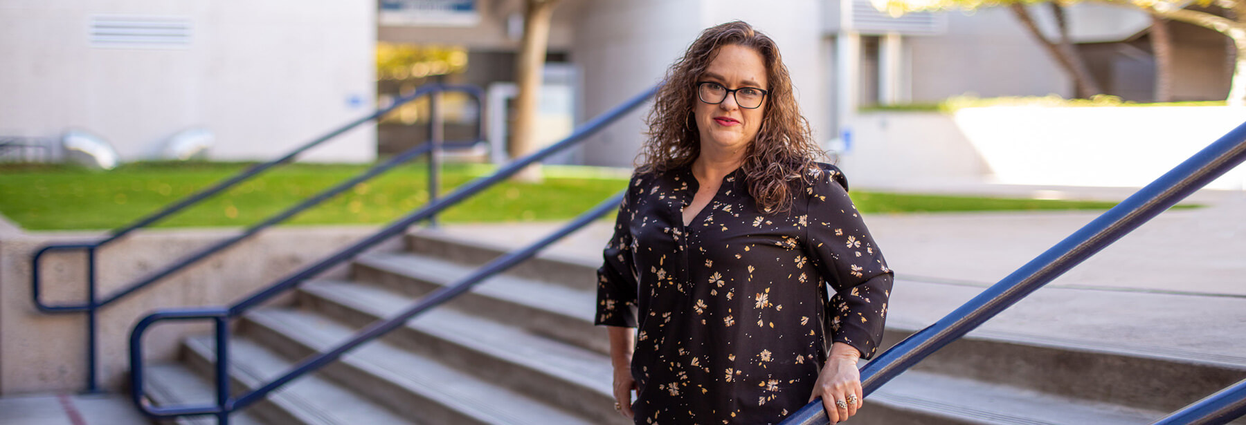 Crystal Robles stands smiling in the courtyard of West Campus