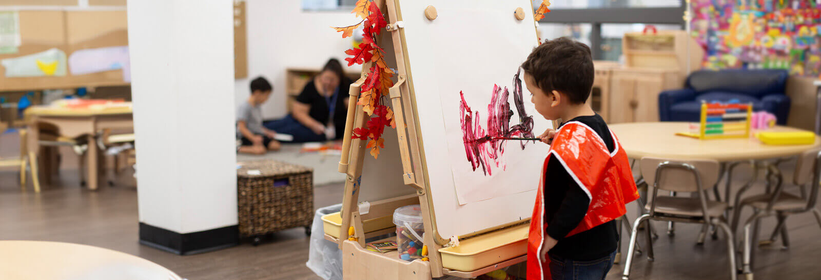 A toddler paints on a canvas in the DV Child Care center