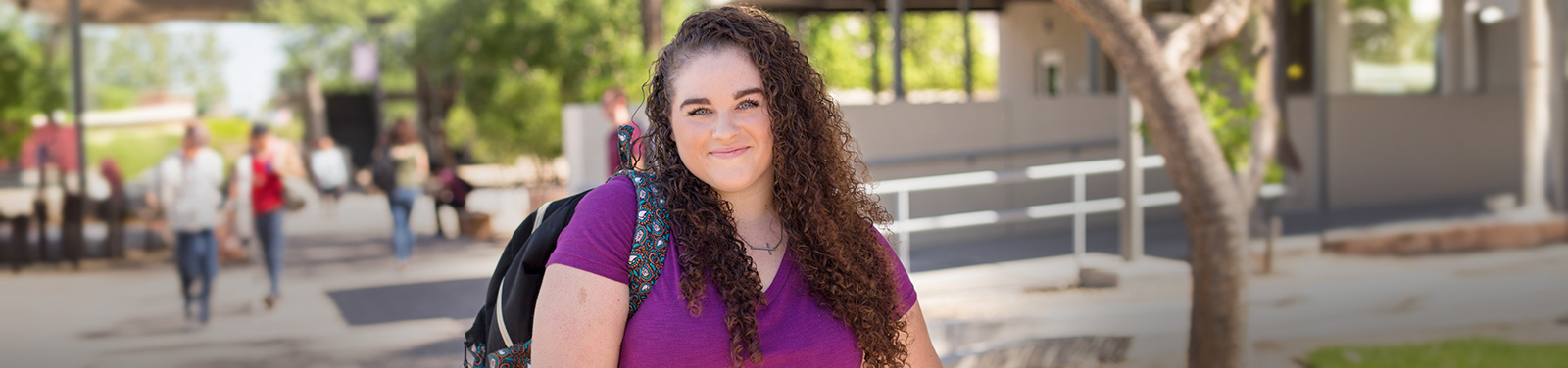 A female student stands smiling at the Downtown Campus Courtyard