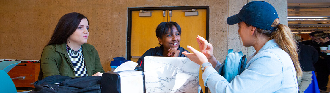 3 students speak ASL in a student lounge at Pima's West Campus