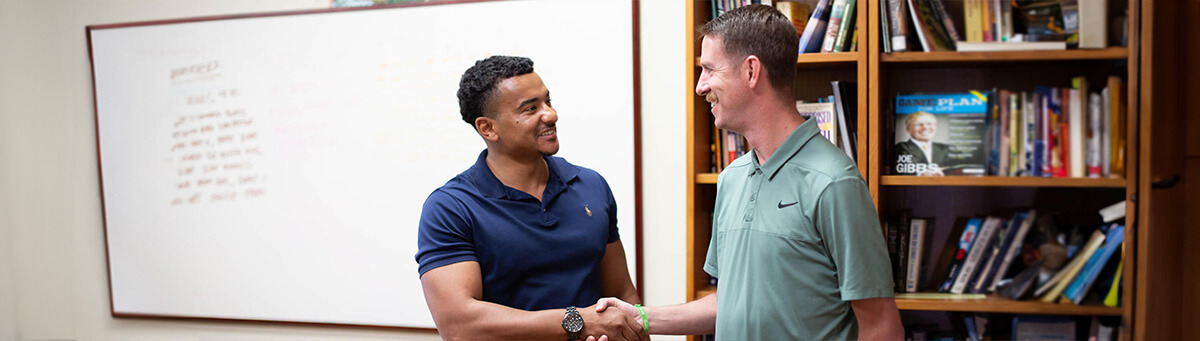 A student speaks to a professor in a classroom