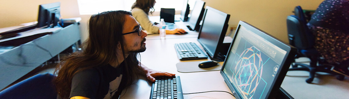 A Pima student sits at a computer with a CAD drawing in a Pima class