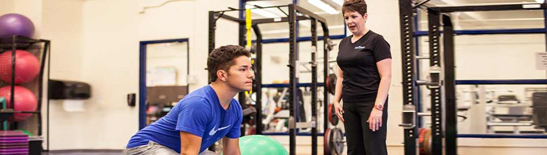 A trainer assists a man with a light fitness workout