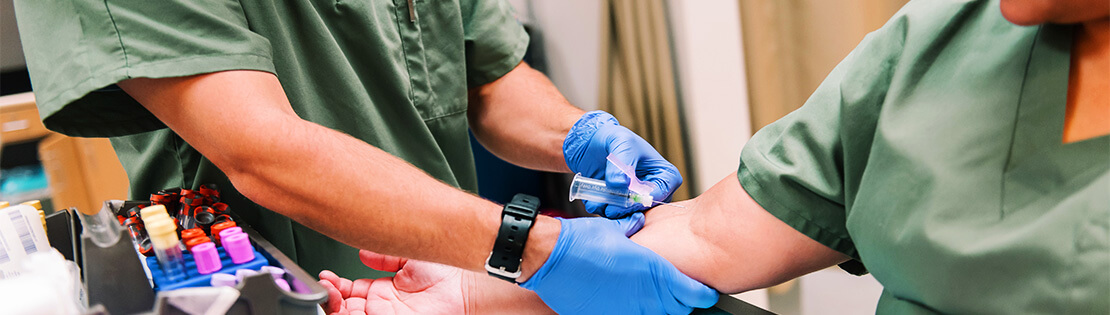 A phlebotomist draws blood from a patient.