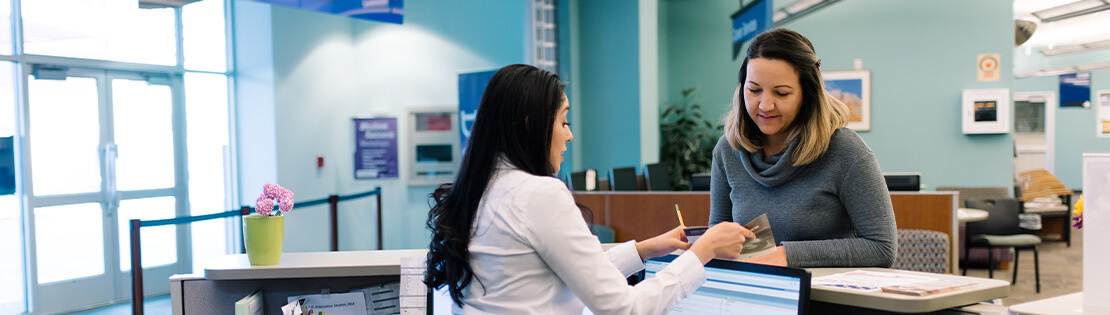 Students look at a computer and chat in a student lounge area