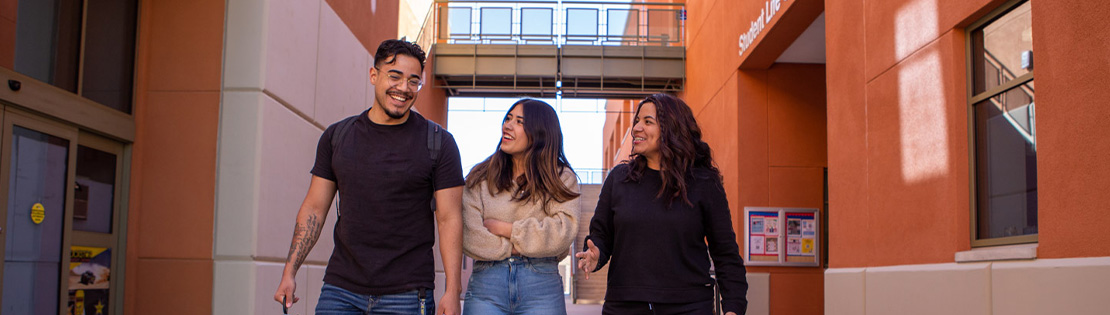 Three Pima students chat while walking to class in a breezeway at Pima's Northwest Campus