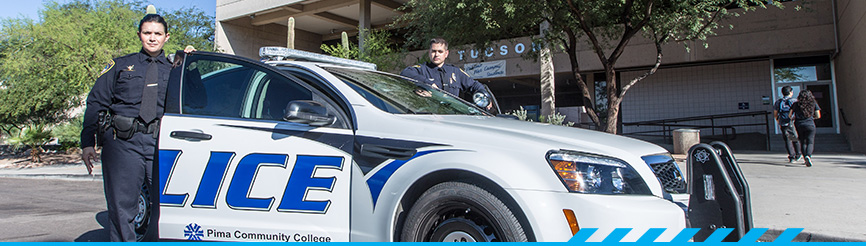 Two campus police stand in front of a squad car