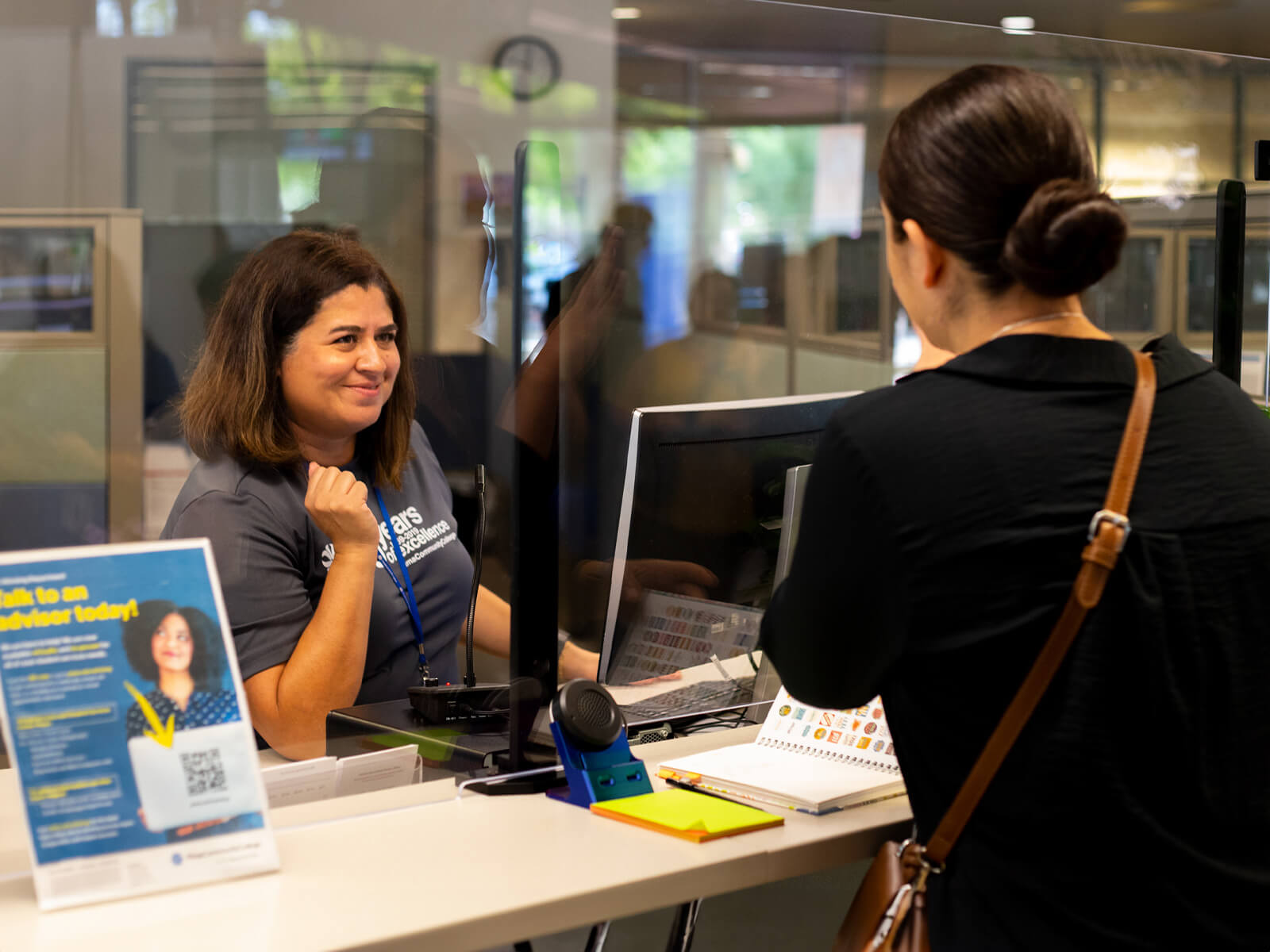 A student asks a front desk assistant at downtown campus for assistance