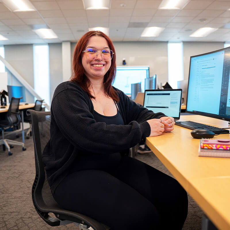 Cathy sits smiling in a Pima classroom in front of a computer