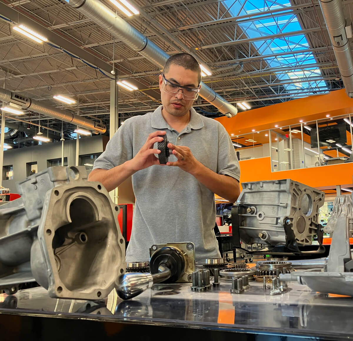 Fernando Romero works on a car component at a work table in the ATIC